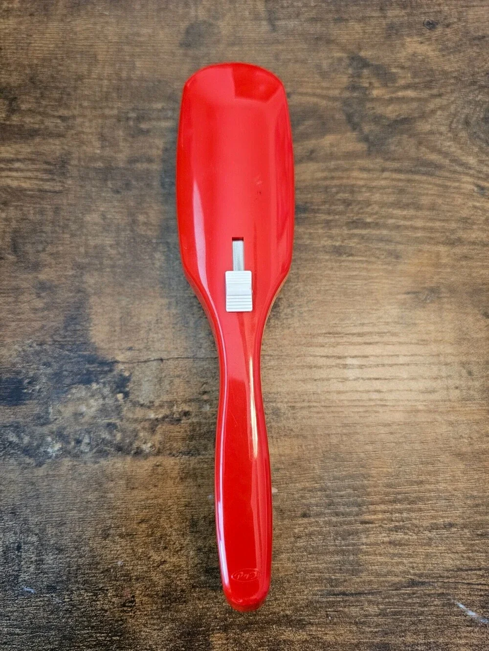 Vintage 1970s hair brush with a red handle and flexible white bristles